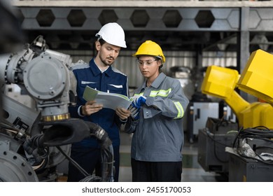 Two focused engineers, a man and a woman, consult a technical document in an industrial setting, emphasizing detail-oriented teamwork in machinery maintenance. - Powered by Shutterstock