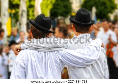 Two folk dancing boys in white shirts and hats