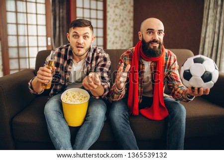 Two football fans wathing tv broadcast at home