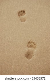 Two Footprints In The Sand On A Beach.