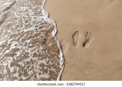 Two footsteps with waves ocean water in the sand on a walk in Maui Hawaii. - Powered by Shutterstock