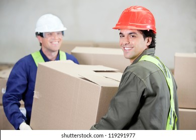 Two Foremen Lifting Cardboard Box At Warehouse