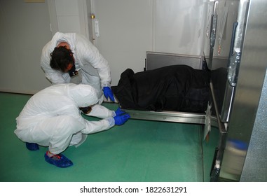 Two forensic workers take the body of a person out of a cold room