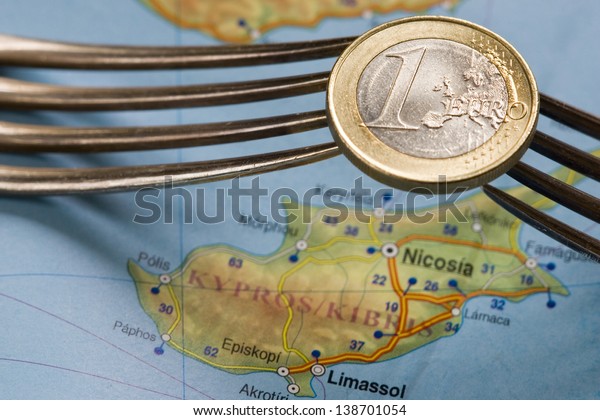 Two forks hold\
one euro coin over Cyprus\
map.