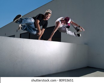 two free-runners jumping over a wall - Powered by Shutterstock