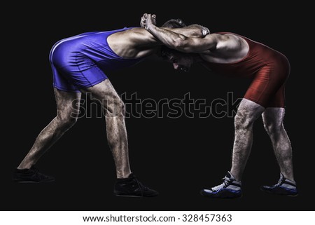 Two freestyle wrestlers in red and blue wrestling uniform isolated on black background