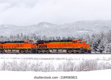 two freight trains, with three locomotives visible, pulling cargo through mountainous region close to Whitefish, Montana in winter - Powered by Shutterstock