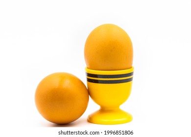 Two fresh brown eggs displayed on bright yellow eggcup isolated on white background. - Shutterstock ID 1996851806