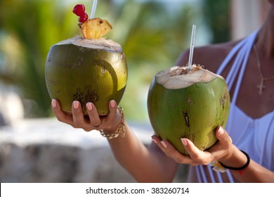 Two fresh coconut cocktails in woman hands. Healthy lifestyle concept.
