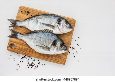 Two Fresh Dorado Fish On Wooden Cutting Board  On White Table. Top View, Copy Space. 