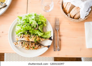 Two freshly barbecued sardines served with lettuce and bread - Shutterstock ID 1203132397