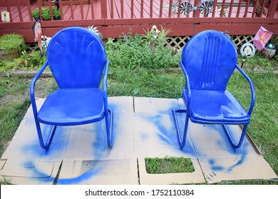 Two Freshly Painted Blue Metal Lawn Chairs In A Yard