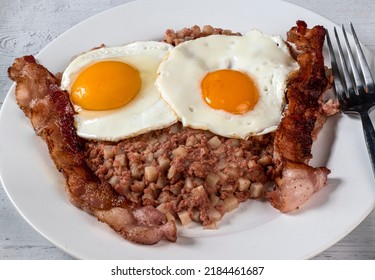 Two Fried Eggs Resting On Corn Beef Hash And Served With Bacon