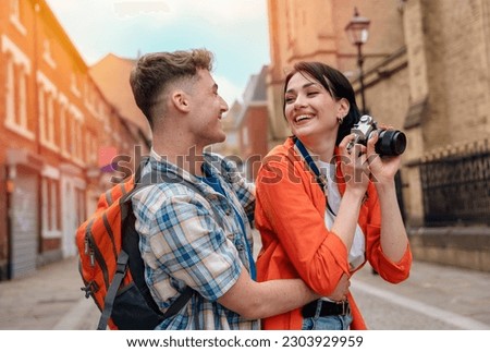 two friend, couple using a camera,   taking selfie against a red phonebox, watching photos on camera, having a fun  in the city of England.Travel Lifestyle concept