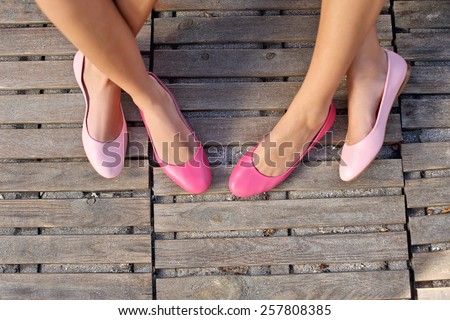 two friend women sitting cross legged wearing pink flats
