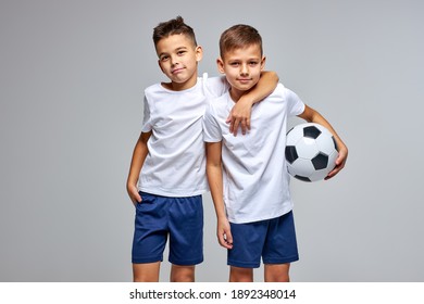 Two Friendly Children Soccer Players Posing At Camera Isolated On Gray Background. Kids Sport Family Leisure Lifestyle Concept. Copy Space Advertisement