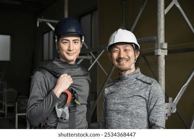 Two friendly workers on site (steeplejacks and outdoor workers with safety belt harnesses) smiling for the camera.