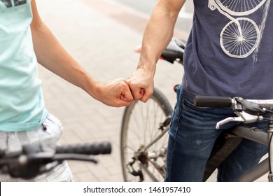 Two friendly young bikers fist bumping each other on the street closeup. Fistbump on the road, bike riding, city tours with friends, friendship and family biking trips concept, eco friendly transport