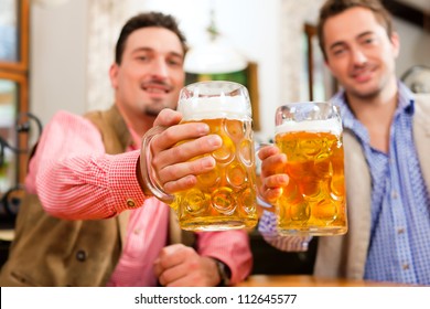 Two friends in Bavarian pub in traditional clothes sitting on their regular table in a pub - Powered by Shutterstock