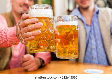 Two friends in Bavarian pub in traditional clothes sitting on their regular table in a pub - Powered by Shutterstock