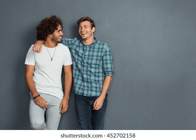 Two friends in casual wear standing and laughing together. Best friends enjoying isolated over grey background. Two men having fun isolated over grey wall with copy space. - Shutterstock ID 452702158