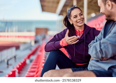 Two friends casually converse while seated at a sports venue, evoking camaraderie.