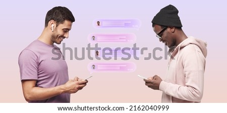 Two friends chatting with each other on smartphone standing against pastel pink background, with text bubbles between them, Caucasian man using earphones, African American guy wearing hat and glasses