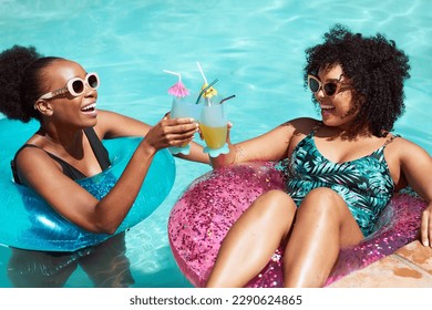 Two friends cheers and clink fancy mocktails in the pool, swimming inflatables - Powered by Shutterstock