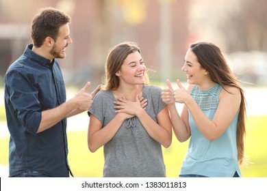 Two friends congratulating a happy girl standing in the street