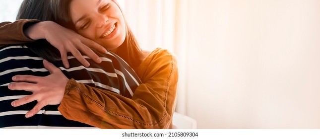 Two friends are embracing in the sun and happy to meet each other. Girls celebrate the holidays or anniversary and hug tightly and warm, feel an emotional connection  and love, smiley face closeup.