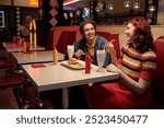 Two friends are enjoying milkshakes and burgers in a classic American diner with red seating booths, decorative elements, and soft lighting, creating a nostalgic atmosphere