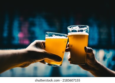 Two Friends Hands Toasting With Glasses Of Light Beer At The Pub Or Bar. Tap Room