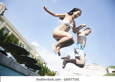 Two Friends Holding Hands And Jumping Into Pool