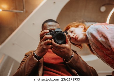 Two friends looking down at their camera which is facing towards the camera - Powered by Shutterstock