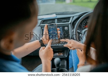 Two friends are looking at a smartphone while driving, planning their exciting journey