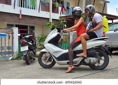 Two friends, lovers, guys sit on bike, motorcycle ready for Songkran, water festival. Teenagers prepare to enjoy water fights, play water pistols, splashes
