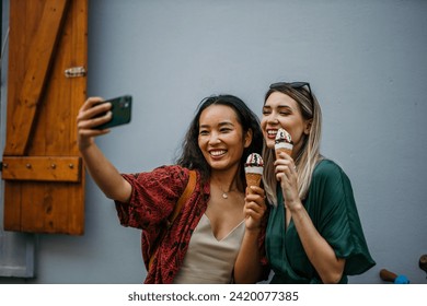 two friends, one Chinese and one Caucasian, sipping ice cream amidst the urban hustle on a warm summer day - Powered by Shutterstock