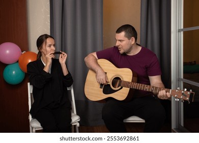 Two friends playing music together, acoustic guitar and harmonica duet, performing live music at home - Powered by Shutterstock