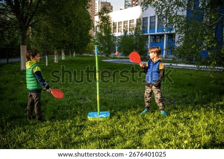 Two friends are playing tetherball swing ball game in summer camping. Two boy brother happy leisure healthy active time outdoors concept.