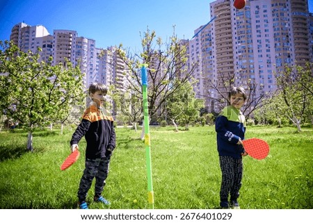 Two friends are playing tetherball swing ball game in summer camping. Two boy brother happy leisure healthy active time outdoors concept.