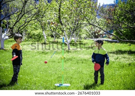Two friends are playing tetherball swing ball game in summer camping. Two boy brother happy leisure healthy active time outdoors concept.