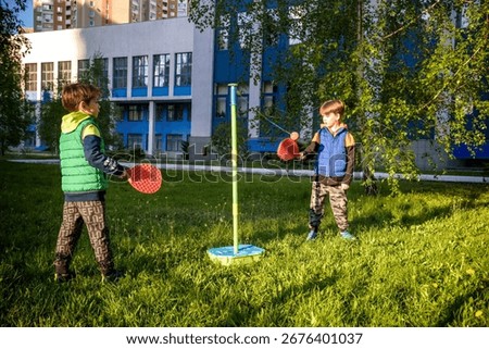 Two friends are playing tetherball swing ball game in summer camping. Two boy brother happy leisure healthy active time outdoors concept.