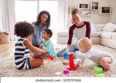 Two friends playing with toddler kids on sitting room floor