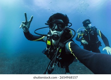 Two friends practicing scuba diving taking selfie, enjoying vacations adventure deep in the ocean