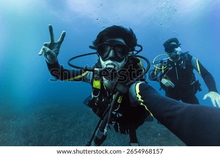 Two friends practicing scuba diving taking selfie, enjoying vacations adventure deep in the ocean
