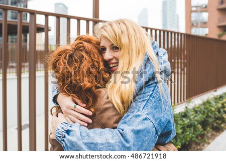 Two friends redhead and blonde girl millennials in the street of the city and hugging Ã¢??friendship, happiness concept