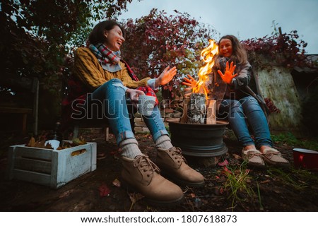 two friends relax comfortably and drink wine on an autumn evening in the open air by the fire in the backyard. The concept of autumn, friendship. top view of the legs