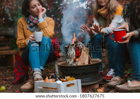 two friends relax comfortably and drink wine on an autumn evening in the open air by the fire in the backyard. The concept of autumn, friendship. top view of the legs