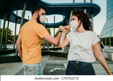 
Two Friends Reuniting After A Long Time After The Quarantine Caused By The Covid19. They Wear A Surgical Mask And Greet Each Other With The Elbow. New Normal