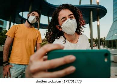 
Two Friends Reuniting After A Long Time After The Quarantine Caused By The Covid19. They Wear A Surgical Mask And Take Photos Together With Social Distance